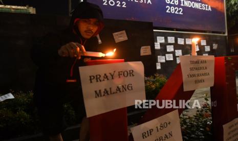 Seorang suporter menyalakan lilin dalam aksi keprihatinan Tragedi Stadion Kanjuruhan di depan Kantor Kementerian Pemuda dan Olah Raga (Kemenpora), Jakarta, Ahad (2/10/2022). Aksi gabungan dari sejumlah kelompok suporter lintas klub sepak bola tersebut menuntut pemerintah dan aparat hukum mengusut tuntas secara adil dan menghukum semua yang bertanggung jawab atas kasus kerusuhan usai pertandingan Arema lawan Persebaya pada Sabtu (1/10) malam di Stadion Kanjuruhan, Malang, Jawa Timur. 