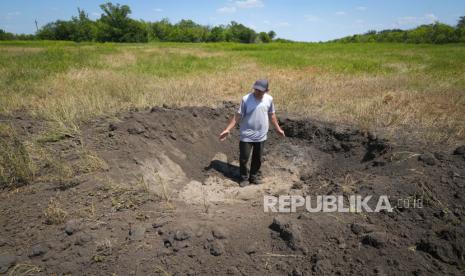 Petani Serhiy, produsen biji-bijian lokal, menunjukkan kawah yang ditinggalkan oleh cangkang Rusia di ladangnya di desa Ptyche di wilayah Donetsk timur, Ukraina, Minggu, 12 Juni 2022. Serhiy mengklaim dia tidak bisa menjual biji-bijiannya karena tidak ada yang mau datang ke daerah yang telah berada di bawah penembakan Rusia. Ukraina adalah salah satu pengekspor gandum dan jagung terbesar di dunia, tetapi invasi Rusia dan blokade pelabuhannya telah menghentikan sebagian besar aliran itu.