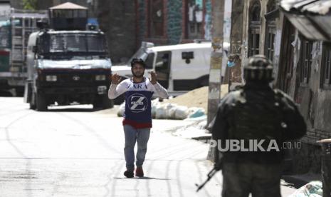 Seorang anak lelaki Muslim Kashmir melarikan diri untuk keselamatan dengan mengangkat tangannya di lokasi konflik di daerah pusat kota Srinagar, Kashmir, India, Selasa (19/5). Menurut laporan setempat, dua gerilyawan tewas dan dua personil keamanan terluka dalam persitiwa baku tembak itu