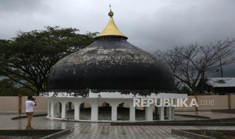 Fotografer mengabadikan kubah masjid yang terdampar akibat gelombang tsunami 26 Desember 2004 di Desa Gurah, Peukan Bada, Aceh Besar, Aceh, Selasa (20/12/2022). Untuk menjaga dan merawat situs kubah masjid yang terbawa gelombang tsunami sejauh dua kilometer pada 18 tahun lalu itu, pemerintah telah telah membangun sarana dan prasarana kawasan objek wisata tersebut dengan anggaran Rp6,4 miliar lebih pada tahun 2022. 