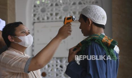 Petugas mengukur suhu tubuh warga sebelum melaksanakan Salat Jumat di Masjid Jami