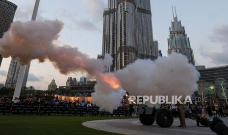 Petugas polisi Dubai menembakkan meriam 25-pounder buatan Inggris tahun 1940 sebagai tanda berbuka puasa di hari pertama bulan suci Ramadhan di depan Burj Khalifa di Teluk Emirat Dubai, Uni Emirat Arab, (23/3/2023). 