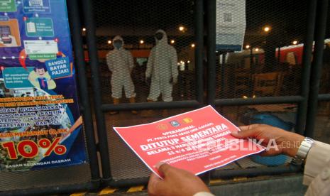 Personel Satpol PP bersiap memasang stiker penutupan sementara cafe Mie Gacoan. (Ilustrasi)