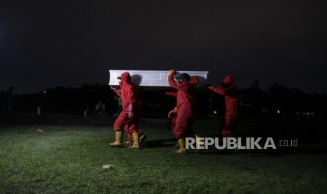 Pekerja yang mengenakan jas hazmat membawa peti mati korban Covid-19 dari ambulans selama pemakaman di pemakaman khusus Bambu Apus Covid-19 di Jakarta, Indonesia, 27 Januari 2021. Indonesia telah melaporkan lebih dari satu juta kasus COVID-19 sejak itu. awal pandemi, jumlah tertinggi di Asia Tenggara.