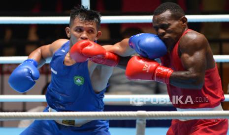 Petinju DKI Jakarta Michael Ronaldo (kiri) melepaskan pukulan ke arah petinju Jawa Timur Mendy Yikwa (kanan) pada delapan besar tinju kelas 64-69 kg putra PON Papua di GOR Cenderawasih, Kota Jayapura, Papua, Jumat (8/10/2021). 