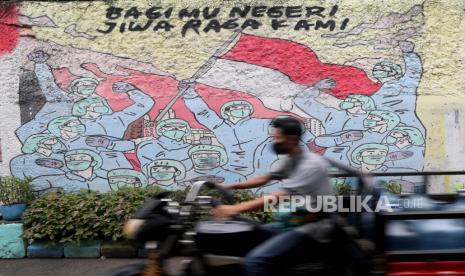  Seorang pria mengendarai sepeda motornya melewati mural kampanye Covid-19 di Tanggerang, Banten.  Presiden Joko Widodo (Jokowi) menekankan percepatan vaksinasi dan menerapkan protokol kesehatan secara ketat adalah kunci utama dalam mengendalikan pandemi Covid-19. 