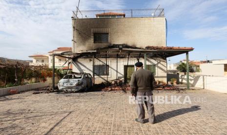 Fle foto seorang warga Palestina memeriksa kerusakan sebuah rumah dan sebuah mobil yang dibakar semalam di desa Turmusayya, dekat kota Ramallah di Tepi Barat, 29 Januari 2023.  Pemukim Yahudi Israel memblokir pintu masuk utama ke Kota Ramallah dan Al-Bireh di pos pemeriksaan militer Beit El di Tepi Barat tengah pada Senin (10/4/2023) malam.