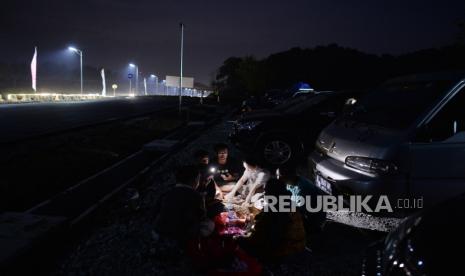 Pemudik berbuka puasa dengan bantuan penerangan senter dari telepon genggam saat beristirahat di Rest Area Sementara 81A Tol Cipali arah Palimanan, Jawa Barat, Selasa (18/4/2023). Keberadaan Rest Area Sementara itu untuk memecah kepadatan pemudik di Rest Area yang ada di jalur Tol Cipali. Nantinya, Rest Area Sementara itu akan dibangun secara permanen menjadi Rest Area dengan kategori Grade A.