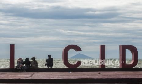 Wisatawan lokal menikmati pemandangan Gunung Rakata dari Pantai Cidatu Carita, Pandeglang, Banten, Ahad (6/2/2022). Pengelola pantai setempat mengatakan kunjungan wisatawan dari luar daerah saat hari libur cenderung sepi akibat adanya aktivitas erupsi Gunung Anak Krakatau (GAK) di perairan Selat Sunda dalam beberapa hari terakhir. 