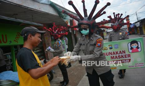 Anggota polisi lalu lintas Polres Mojokerto membagikan masker saat sosialisasi penggunaan masker dengan memakai helm virus corona di pasar tradisional Sawahan, Kecamatan Bangsal, Kabupaten Mojokerto, Jawa Timur, Rabu (8/4/2020). Polres Mojokerto memakai cara unik untuk menyadarkan masyarakat terkait kewajiban menggunakan masker saat keluar rumah serta membagi masker gratis untuk mengantisipasi penyebaran COVID-19