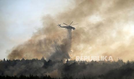  Helikopter menjatuhkan air di atas api di daerah Varibobi, Athena utara, Yunani, Rabu, 4 Agustus 2021. Pesawat pemadam kebakaran melanjutkan operasi pada Rabu cahaya pertama untuk mengatasi kebakaran hutan besar di pinggiran utara Athena yang melaju ke daerah pemukiman hari sebelumnya, memaksa ribuan orang meninggalkan rumah mereka di tengah gelombang panas terburuk Yunani dalam beberapa dekade.