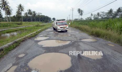 Pengendara mobil melintas di antara jalan berlubang yang tergenang air di jalan terusan Ryacudu Jati Agung, Lampung Selatan Lampung, Rabu (3/5/2023). Sejumlah titik jalur akses menuju Kota Baru Lampung, mengalami kerusakan sehingga membahayakan kesalamatan pengendara yang nelintas jalur tersebut.