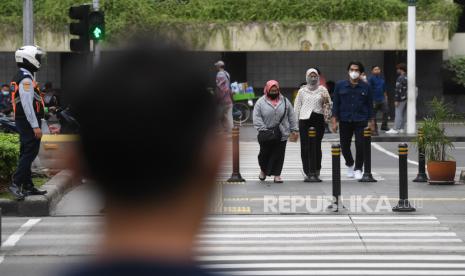 Warga mengenakan masker saat melintas di Jalan MH Thamrin, Jakarta, Rabu (12/1/2022). Kemenkes memprediksi puncak penyebaran kasus COVID-19 varian Omicron akan terjadi pada awal atau pertengahan Februari 2022. 