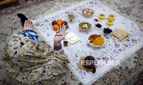  Seorang wanita lanjut usia berdoa di samping hidangan berbuka puasa di rumah mereka selama Ramadhan di Teheran, Iran, 23 Maret 2023 (diterbitkan 25 Maret 2023). 