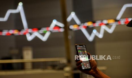 Pengunjung mengamati data saham melalui aplikasi IDX Mobile di dekat layar yang menampilkan indeks harga saham gabungan (IHSG).