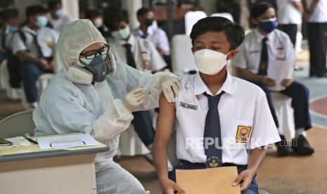 Seorang pekerja medis memberikan suntikan vaksin Covid-19 kepada seorang siswa. 