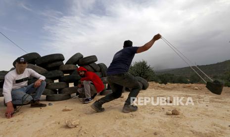 A P Seorang Palestina melemparkan batu ke pasukan Israel saat bentrokan setelah protes terhadap pemukim Israel yang berunjuk rasa di dekat pos ilegal Avitar, dekat desa Beita di Tepi Barat, Senin (10/4/2023). Dua puluh lima warga Palestina terluka dalam bentrokan tersebut, kata kementerian kesehatan Palestina. alestinian hurls stones at Israeli troops during clashes after a protest against Israeli settlers rallying near the illegal outpost of Avitar, near the West Bank village of Beita, 10 April 2023. Twenty-five Palestinians were wounded during the clashes, the Palestinian health ministry said. The clashes followed a rally near Avitar outpost which was attended by Israeli far-right supporters, Israeli Ministers and Knesset members attended  