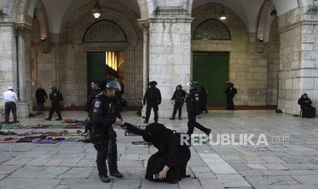  Seorang polisi wanita Israel menarik seorang jamaah wanita yang sedang duduk di tanah di kompleks Masjid Al-Aqsa setelah penggerebekan di lokasi tersebut pada bulan suci Ramadhan di Kota Tua Yerusalem, Rabu (5/4/2023) .