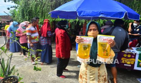 Warga menunjukkan minyak goreng kemasan saat pasar murah di Desa Gulang, Mejobo, Kudus, Jawa Tengah, Ahad (6/3/2022). Pasar murah minyak goreng yang digelar Pemdes setempat itu menyediakan sebanyak 5000 liter dengan harga Rp14.000 per liter, sebagai upaya membantu masyarakat mendapatkan harga yang lebih terjangkau. 