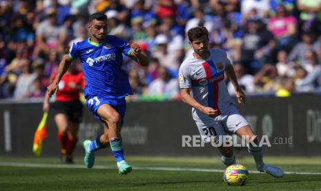  Pemain Barcelona Sergi Roberto (kanan) berlari dengan bola melewati pemain Getafe Juan Iglesias pada pertandingan sepak bola La Liga Spanyol antara Getafe dan FC Barcelona di stadion Coliseum Alfonso Perez di Getafe, Spanyol,  Ahad (17/4/2023) malam WIB.