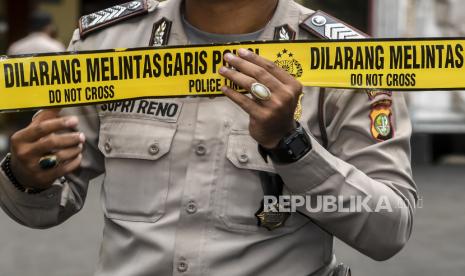 Petugas kepolisian memasang batas garis polisi di area tempat kejadia perkara (TKP) pengeroyokan salah sasaran.