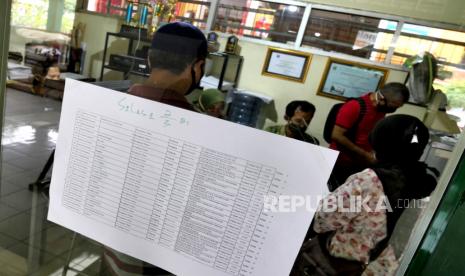 Pedagang memeriksa jadwal vaksinasi Covid-19 di Pasar Beringharjo, Yogyakarta, Ahad (28/2). Presiden Joko Widodo (Jokowi) akan meninjau pelaksanaan program vaksinasi massal bagi pekerja publik di Yogyakarta pada Senin (1/3).