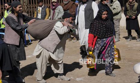  Warga Afghanistan membawa perbekalan makanan saat pendistribusian bantuan kemanusiaan untuk keluarga yang membutuhkan, di Kabul, Afghanistan, Rabu, 16 Februari 2022. Afghanistan telah mengalami transformasi dramatis dalam setengah tahun pemerintahan Taliban. Negara ini merasa lebih aman dan tidak terlalu keras dibandingkan dalam beberapa dasawarsa, tetapi juga lebih miskin karena ekonomi yang dulunya didorong oleh bantuan menuju keruntuhan.