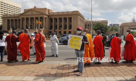 Seorang pria memegang plakat bertuliskan mengapa presiden takut pada menteri kehakiman saat protes oleh biksu Buddha Sri Lanka yang pro-pemerintah di luar kantor presiden meminta pemerintah untuk tidak meninjau kebijakan wajib kremasi bagi korban COVID-19 Muslim, di Kolombo, Sri Lanka, Senin, 28 Desember 2020. 