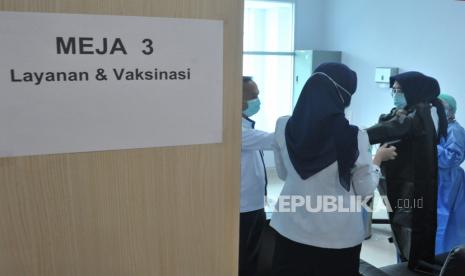 Sejumlah petugas membantu penerima vaksin bersiap di ruang layanan vaksin pada pelaksanaan perdana vaksinasi Covid-19 (ilustrasi)