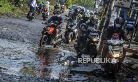 Sejumlah pengendara motor menghindari genangan air akibat jalan yang berlubang di kawasan Bojong Gede, Kabupaten Bogor, Jawa Barat, Senin (28/9). Jalanan berlubang yang sudah beberapa kali mengalami kerusakan itu belum juga diperbaiki sehingga dapat membahayakan keselamatan pengendara, menimbulkan genangan air ketika hujan dan menghambat arus lalu lintas kendaraan. Republika/Putra M. Akbar