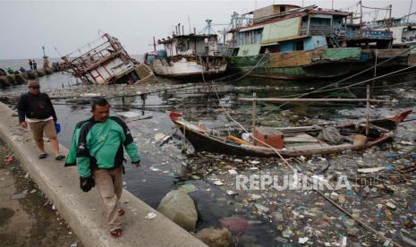 Warga berjalan melewati perairan Jakarta yang penuh sampah, terutama sampah plastik, di pelabuhan tradisional Muara Baru di Jakarta, (iustrasi).