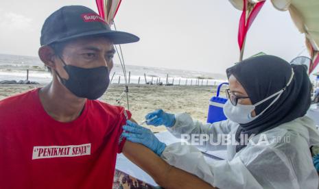 Vaksinator menyuntikkan vaksin COVID-19 saat pelaksanaan vaksinasi massal di objek wisata Pantai Sedari, Cibuaya, Karawang, Jawa Barat, Ahad (8/8/2021). Pemerintah Kabupaten Karawang bersama TNI, Polri dan Toyota Indonesia menggelar vaksinasi massal dengan menyediakan sedikitnya 1500 dosis vaksin COVID-19 untuk masyarakat pesisir guna mencegah lonjakan kasus COVID-19. 