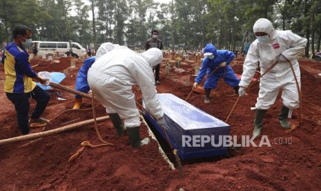 Pekerja dengan alat pelindung menurunkan peti mati korban COVID-19 ke kuburan untuk dimakamkan di Pemakaman Cipenjo di Bogor, Jawa Barat, Indonesia, Rabu, 14 Juli 2021.