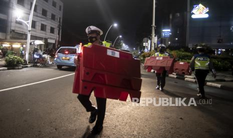 Petugas kepolisian mengangkat pembatas jalan saat akan melakukan penutupan jalan dalam rangka pembatasan mobilitas warga guna menekan penyebaran COVID-19 di kawasan Bulungan, Jakarta, Senin (21/6/2021). Pada September ini, Polda Metro Jaya akan memberlakukan crowd free night di beberapa ruas jalan di Jakarta setiap Jumat-Minggu malam. (ilustrasi)