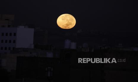 Bulan purnama terbenam di atas lingkungan di Sana