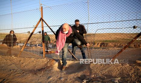  Warga Palestina melintasi pagar keamanan Israel ke daerah Israel dekat kota Hebron, Tepi Barat, Ahad (31/1/2021). Otoritas Palestina (PA) memulai vaksinasi Covid-19 di Tepi Barat yang diduduki pada Selasa (2/2/2021).