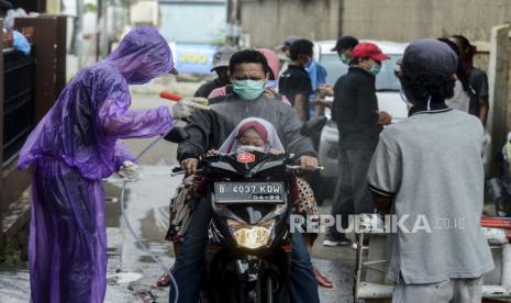 Warga menyemprotkan cairan disinfektan kepada pengendara motor yang akan menuju Kampung Cakung di kawasan Jatiasih, Bekasi, Jawa Barat, Ahad (29/3). Kampung Cakung menerapkan isolasi mandiri di wilayahnya dengan menutup sejumlah ruas jalan menuju kampung dan menyemprotkan cairan disinfektan kepada warga yang akan kembali ke rumahnya untuk memutus mata rantai penyebaran Corona atau Covid-19