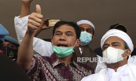  FILE - Pada file foto Sabtu 12 Desember 2020 ini, Sekretaris Jenderal Front Pembela Islam Munarman, kiri, yang juga pengacara ulama Rizieq Shihab, kanan, memberi isyarat kepada wartawan setelah Rizieq diinterogasi di Polda Kantor pusat di Jakarta, Indonesia. Anggota pasukan polisi kontraterorisme Indonesia pada hari Selasa 27 April 2021