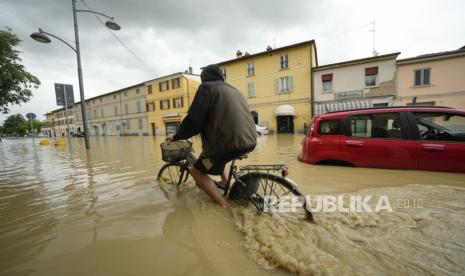 Seorang pengendara sepeda melewati jalan yang banjir di desa Castel Bolognese, Italia, Rabu (17/5/2023). Hujan yang luar biasa pada hari Rabu di wilayah yang dilanda kekeringan di Italia utara membuat sungai meluap di tepiannya, menewaskan sedikitnya delapan orang, memaksa evakuasi ribuan dan mendorong pejabat untuk memperingatkan bahwa Italia membutuhkan rencana nasional untuk memerangi banjir akibat perubahan iklim.