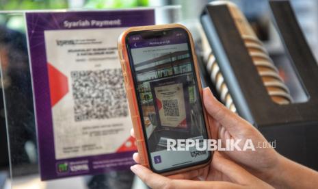 seorang pengunjung memindai QRIS (ilustrasi). Pengamat menilai masih ada ruang bagi Bank Indonesia untuk menurunkan suku bunga.