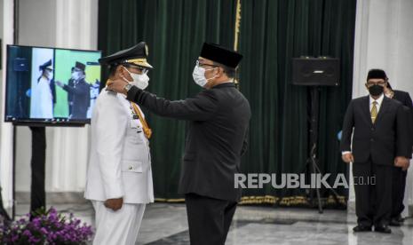 Gubernur Jawa Barat Ridwan Kamil (kanan) menyematkan tanda jabatan kepada Wali Kota Tasikmalaya Muhammad Yusuf (kiri) saat upacara pengambilan sumpah jabatan dan pelantikan Wali Kota Tasikmalaya di Gedung Sate, Kota Bandung, Jumat (10/9). Muhammad Yusuf dilantik sebagai Wali Kota Tasikmalaya oleh Gubernur Jawa Barat Ridwan Kamil dengan sisa masa jabatan periode 2017-2022. Foto: Republika/Abdan Syakura