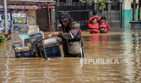 Seorang pedagang tahu menerjang banjir yang melanda Kampung Bojongasih, Dayeuhkolot, Kabupaten Bandung, Jawa Barat, Selasa (19/4/2022). Sebanyak 13 RW di Desa Dayeuhkolot dan ribuan jiwa terdampak banjir akibat luapan Sungai Citarum akibat hujan deras di Bandung Raya pada Senin (18/4/2022) malam. 