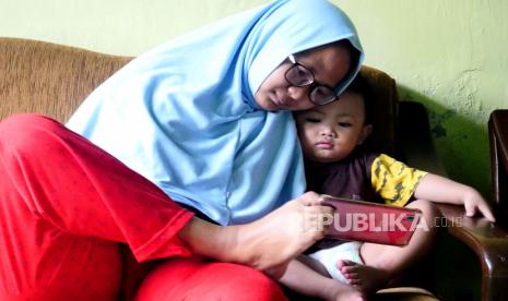 Ilustrasi ibu dan anak menonton gawai. Terlalu sering menonton gawai dapat menyebabkan speech delay pada anak.