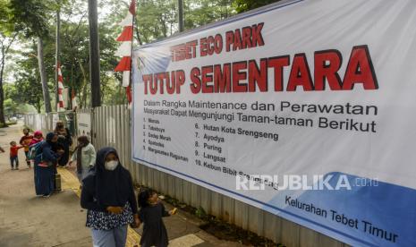 Warga berjalan di dekat spanduk informasi penutupan sementara Tebet Eco Park di Tebet, Jakarta, Rabu (15/6/2022). Pemerintah Provinsi DKI Jakarta menutup sementara Tebet Eco Park hingga akhir Juni 2022 dalam rangka pemeliharaan taman dan perbaikan fasilitas. Republika/Putra M. Akbar 