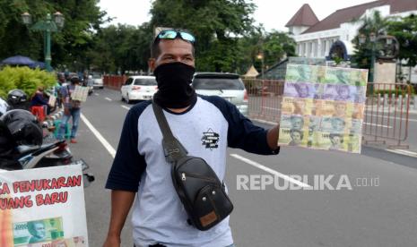 Pedagang menunggu konsumen untuk jasa penukaran mata uang baru di Kawasan Titik Nol,  Yogyakarta, Selasa (19/5). Pada tahun ini minat warga menukar uang baru sangat sedikit dibanding tahun lalu