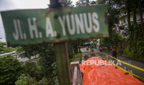 Warga berjalan di dekat jalan longsor yang ditutupi terpal di Jalan H. A. Yunus, Kota Bogor, Jawa Barat, Senin (12/9/2022). Jalan alternatif penghubung Kota Bogor dan Kabupaten Bogor tersebut longsor yang diakibatkan tingginya curah hujan sehingga hanya dapat dilewati kendaraan roda dua.