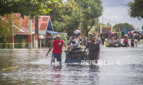 Warga menggunakan jasa gerobak angkut untuk melintas di Jalan Trans Kalimantan yang terendam banjir di Desa Banua Raya, Kecamatan Bati-Bati, Kabupaten Tanah Laut, Kalimantan Selatan, Senin (11/1/2021). Banjir yang melanda sejumlah kawasan di Kecamatan Bati Bati mengakibatkan jalan Trans Kalimantan yang menghubungkan Kota Banjarmasin-Kabupaten Tanah Bumbu dan Provinsi Kalimantan Timur tersebut lumpuh akibat terendam banjir. 