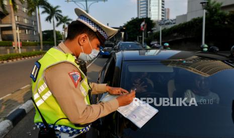 Petugas Kepolisian melakukan penindakan tilang manual terhadap pengemudi yang melakukan pelanggaran.