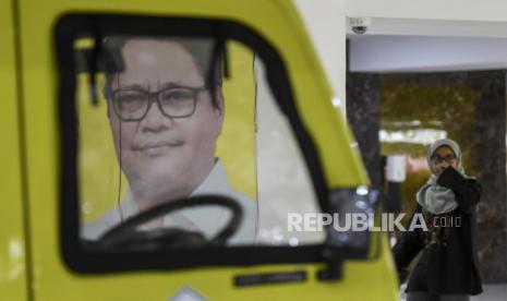 Pekerja melintas di dekat poster Airlangga Hartarto di DPP Partai Golkar, Jakarta, Ahad (11/8/2024). Airlangga Hartarto mengundurkan diri dari jabatan Ketua Umum Partai Golkar.