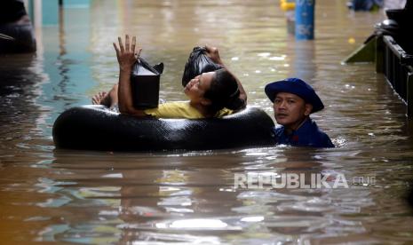 Petugas membantu warga melintasi melintasi banjir yang merendam kawasan Kebon Pala, Kampung Melayu, Jatinegara, Jakarta Timur, Senin (27/2/2023). Banjir setinggi 1-2 meter tersebut terjadi akibat luapan kali ciliwung yang dipicu air kiriman dari Bogor dan Depok. 